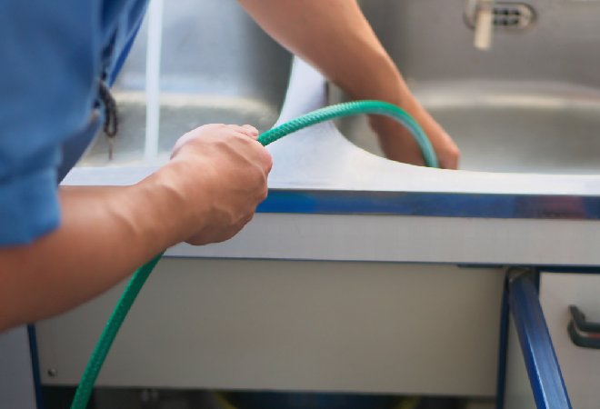 ホースを使ってシンクの詰まりを修理する男性の手。