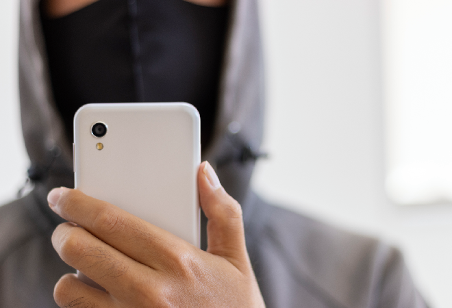 黒いマスクをつけた男性がこちらにスマホのカメラを向けている画像。