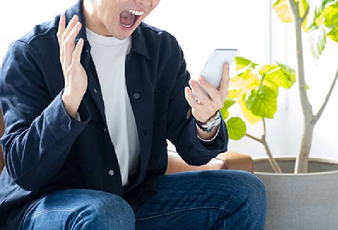 スマホを見て驚く男性。